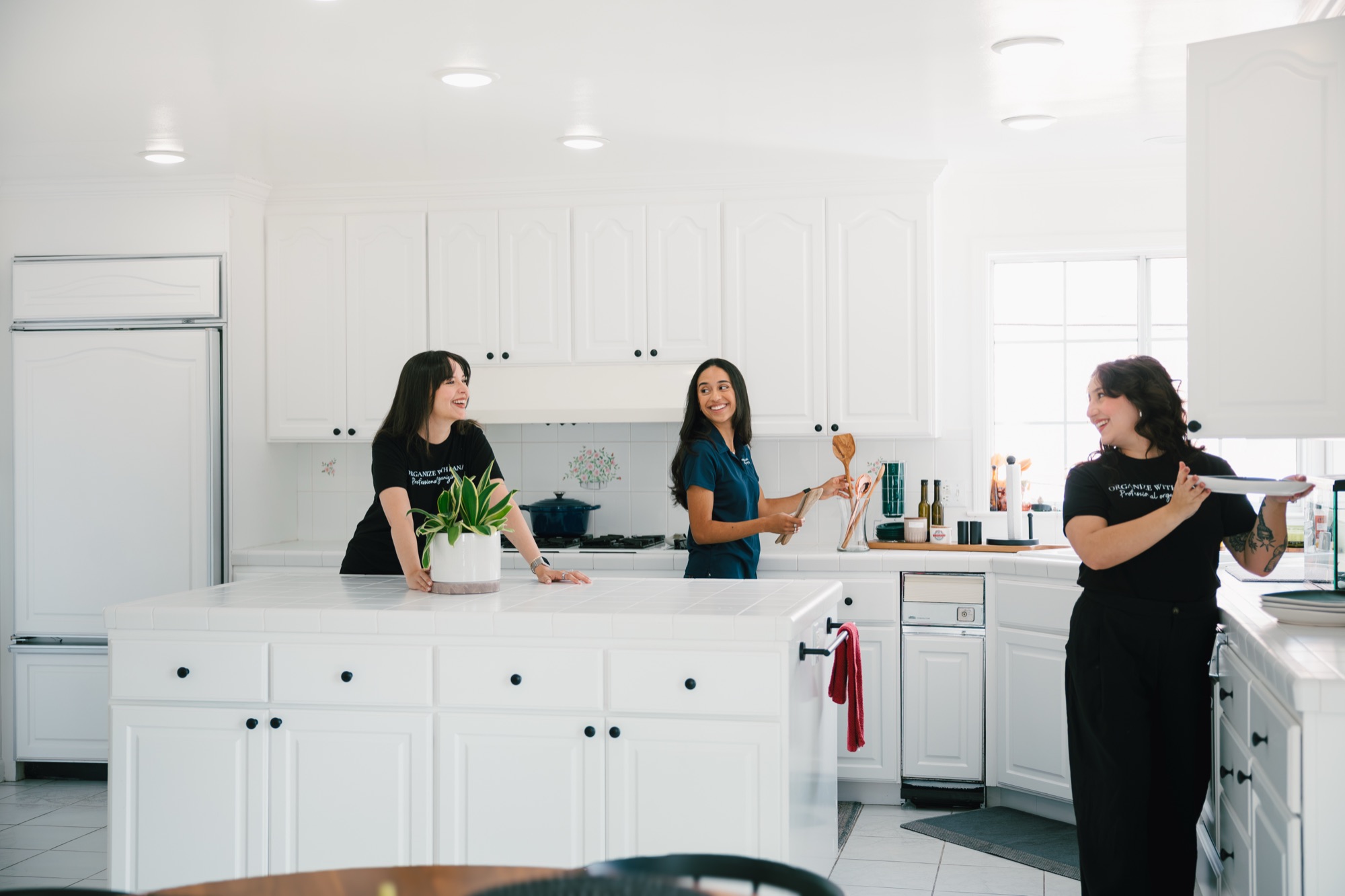 Three Organize with Lana team members talking together around the island of a bright white kitchen